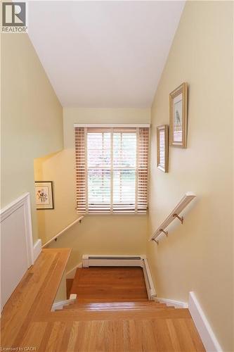 Hardwood staircase with natural wood flooring, white baseboards, and a window with wood blinds - 2023 Coronation Boulevard, Cambridge, ON - Indoor Photo Showing Other Room