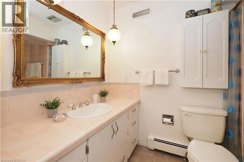 Bathroom vanity with an integrated basin, a large ornate gold-framed mirror, and two hanging pendant light fixtures - 2023 Coronation Boulevard, Cambridge, ON - Indoor Photo Showing Bathroom