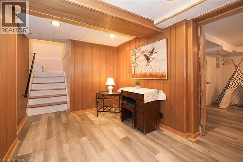 Finished lower level featuring wood-finish flooring, paneled walls, recessed lighting, a white staircase with a dark handrail, and an adjacent room with a built-in platform - 2023 Coronation Boulevard, Cambridge, ON - Indoor Photo Showing Other Room