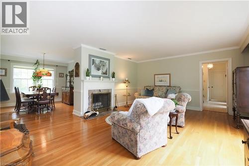Living area featuring hardwood flooring, a fireplace with a white mantel and stone surround, and an open doorway to another room - 2023 Coronation Boulevard, Cambridge, ON - Indoor Photo Showing Living Room With Fireplace