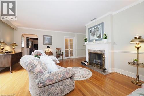 Bright living space featuring hardwood flooring, a white mantel fireplace with a stone surround, an arched doorway, and French doors - 2023 Coronation Boulevard, Cambridge, ON - Indoor With Fireplace