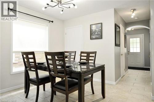 Dining area featuring a contemporary chandelier, a large window, light-toned tile flooring, and an arched entryway to the foyer - 12 Karalee Crescent, Cambridge, ON - Indoor Photo Showing Dining Room