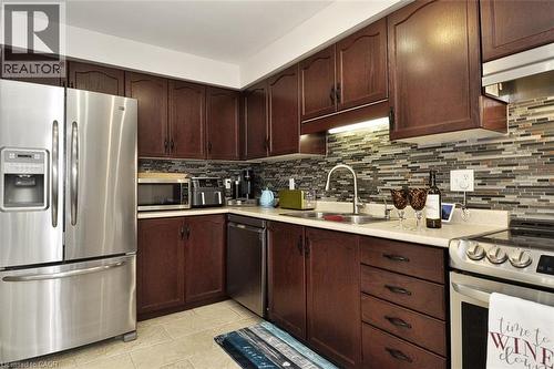 Kitchen featuring dark wood cabinetry, light-toned countertops, and a full tile backsplash - 12 Karalee Crescent, Cambridge, ON - Indoor Photo Showing Kitchen With Double Sink