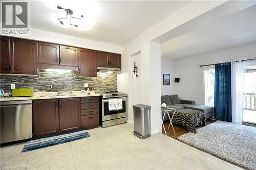 Kitchen featuring dark wood cabinetry, a mosaic tile backsplash, and stainless steel appliances - 12 Karalee Crescent, Cambridge, ON - Indoor Photo Showing Kitchen