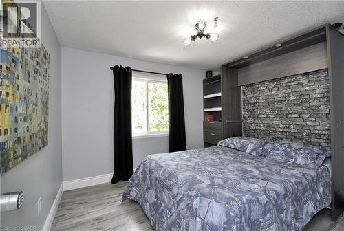 Compact sleeping area featuring a built-in wall unit with a stone-look accent panel, integrated shelving, and drawer storage - 12 Karalee Crescent, Cambridge, ON - Indoor Photo Showing Bedroom