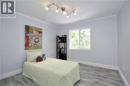 Bedroom featuring wood-finish flooring, a white-framed window, crown molding, track lighting, and light gray wall paint - 12 Karalee Crescent, Cambridge, ON - Indoor Photo Showing Bedroom