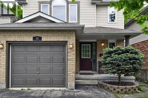 Brick and siding facade featuring an attached garage with a panel door, covered entryway, and an arched window on the upper level - 12 Karalee Crescent, Cambridge, ON - Outdoor