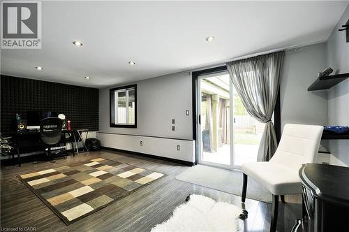 Spacious room featuring wood-finish flooring, recessed ceiling lighting, and a wall of acoustic paneling - 12 Karalee Crescent, Cambridge, ON - Indoor