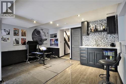 Lower level featuring a wet bar with gray cabinetry, mosaic tile backsplash, and an integrated beverage refrigerator - 12 Karalee Crescent, Cambridge, ON - Indoor Photo Showing Other Room