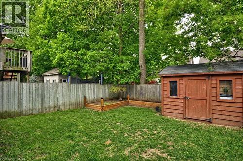 Expansive backyard featuring a manicured lawn, a wood-sided storage shed with double doors, and a raised garden bed - 12 Karalee Crescent, Cambridge, ON - Outdoor