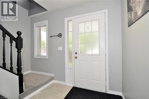 Entryway featuring a white door with frosted glass panels and a sidelight, neutral wall tones, and a staircase with dark wood balusters and a carpeted tread - 12 Karalee Crescent, Cambridge, ON - Indoor Photo Showing Other Room