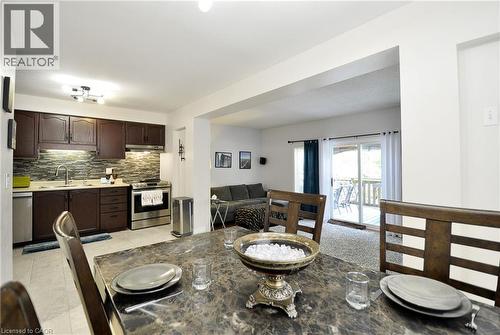 Open-concept dining area featuring a dark-toned table with a polished surface, providing a direct sightline to the kitchen and living spaces - 12 Karalee Crescent, Cambridge, ON - Indoor