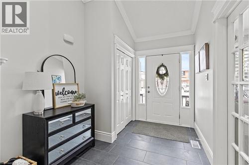 Entryway featuring slate-look floor tile, a white entry door with an oval leaded glass insert, and two vertical sidelight windows - 27 Barbara Court, Hamilton, ON - Indoor Photo Showing Other Room