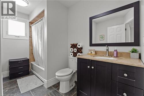 Bathroom featuring a dark wood-finish vanity with a light-toned countertop, an integrated sink, and a large framed mirror - 27 Barbara Court, Hamilton, ON - Indoor Photo Showing Bathroom