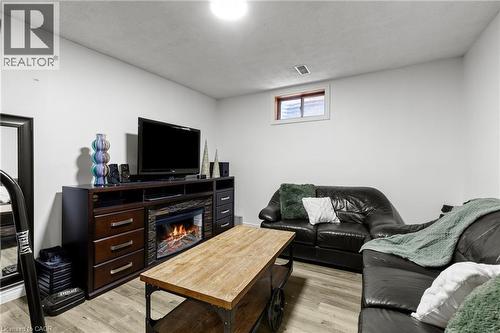 Entertainment area featuring wood-finish flooring, a built-in media console with an electric fireplace, recessed lighting, and a window - 27 Barbara Court, Hamilton, ON - Indoor