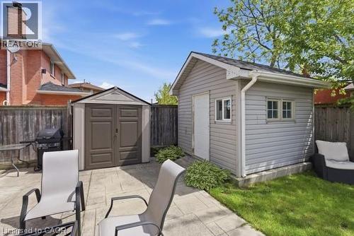 Expansive backyard featuring a gray siding shed with multiple windows, a second storage shed, and a concrete patio - 27 Barbara Court, Hamilton, ON - Outdoor