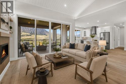 Living Room looking into Kitchen and onto Covered Deck *Virtually Staged* - 2150 Montenegro Drive, Kelowna, BC - Indoor Photo Showing Living Room With Fireplace