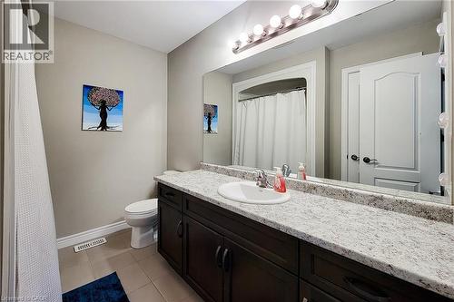 Bathroom featuring a dark wood-finish vanity with a light speckled countertop, an integrated sink, and an expansive mirror - 40 Fairgrounds Drive, Binbrook, ON - Indoor Photo Showing Bathroom