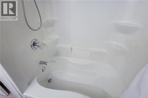 White fiberglass shower and tub combination featuring built-in shelving, a curved tub basin, and chrome fixtures - 40 Fairgrounds Drive, Binbrook, ON - Indoor Photo Showing Bathroom