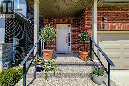 Inviting front entrance featuring a white panel door, exposed aggregate steps, and black metal handrails - 40 Fairgrounds Drive, Binbrook, ON - Outdoor With Deck Patio Veranda With Exterior