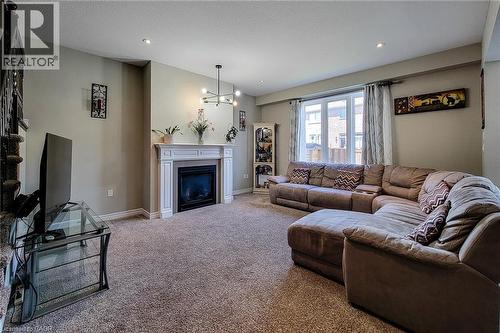 Living area featuring a white mantel fireplace, recessed lighting, and a contemporary chandelier - 40 Fairgrounds Drive, Binbrook, ON - Indoor Photo Showing Living Room With Fireplace
