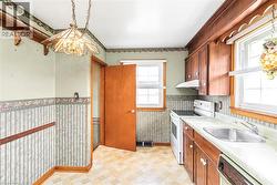 Kitchen featuring wood cabinetry, laminate countertops, and resilient vinyl flooring - 
