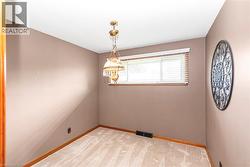 Carpeted room featuring a single window with blinds, a classic chandelier, and wood-finish trim - 