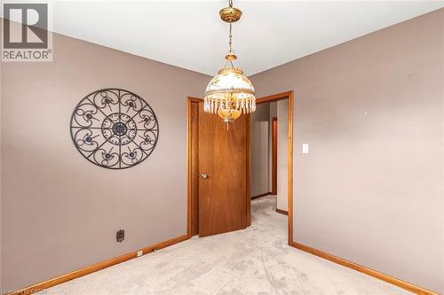Carpeted room featuring a ceiling-mounted chandelier, wood-finish doors, and wood-finish baseboards - 435 East 36Th Street, Hamilton, ON - Indoor Photo Showing Other Room