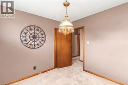 Carpeted room featuring a ceiling-mounted chandelier, wood-finish doors, and wood-finish baseboards - 