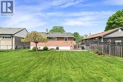 Expansive rear lawn featuring a mature weeping tree and established shrubbery - 