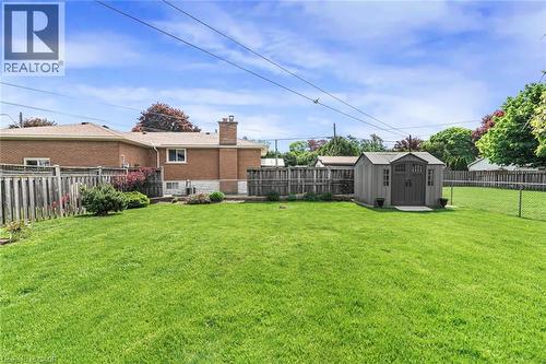 Expansive green lawn featuring a storage shed with double doors, wood fencing, and a chain-link fence - 435 East 36Th Street, Hamilton, ON - Outdoor