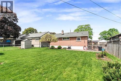 Expansive backyard featuring a manicured lawn, mature trees, a wooden shed, and a privacy fence - 435 East 36Th Street, Hamilton, ON - Outdoor