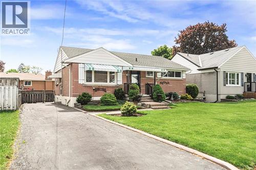 Brick bungalow with front yard landscaping, a paved driveway, and a fenced side yard - 435 East 36Th Street, Hamilton, ON - Outdoor