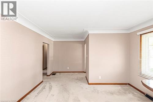 Spacious interior room featuring light gray carpeting, neutral wall tones, white crown molding, and wood-finish baseboards - 435 East 36Th Street, Hamilton, ON - Indoor Photo Showing Other Room