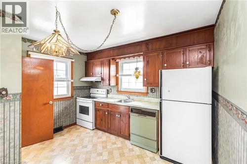 Kitchen featuring wood cabinetry, a built-in range hood, and two windows - 435 East 36Th Street, Hamilton, ON - Indoor Photo Showing Kitchen