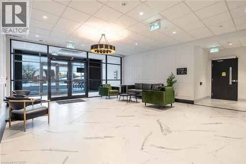 Lobby area featuring large format marble-look tile flooring, contemporary chandelier, full-height glass entrance, and decorative wainscoting - 1936 Rymal Road E Unit# 512, Hamilton, ON - Indoor Photo Showing Other Room
