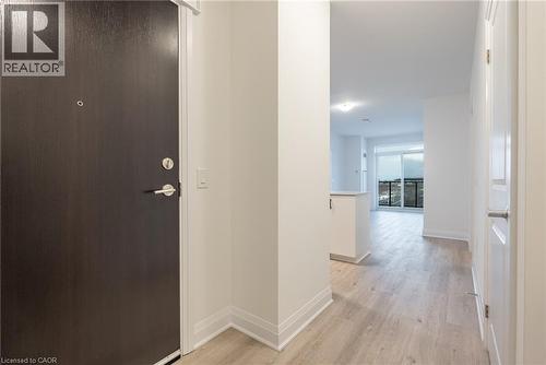 Entryway featuring a dark wood-finish door with brushed nickel hardware, light wood-finish flooring, white baseboards, and neutral wall paint - 1936 Rymal Road E Unit# 512, Hamilton, ON - Indoor Photo Showing Other Room