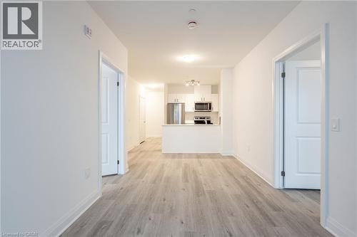 Open-concept living space featuring wood-finish flooring, white walls, and bright overhead lighting - 1936 Rymal Road E Unit# 512, Hamilton, ON - Indoor