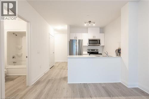Open-concept kitchen featuring white cabinetry, stainless steel appliances, and a breakfast bar - 1936 Rymal Road E Unit# 512, Hamilton, ON - Indoor Photo Showing Kitchen