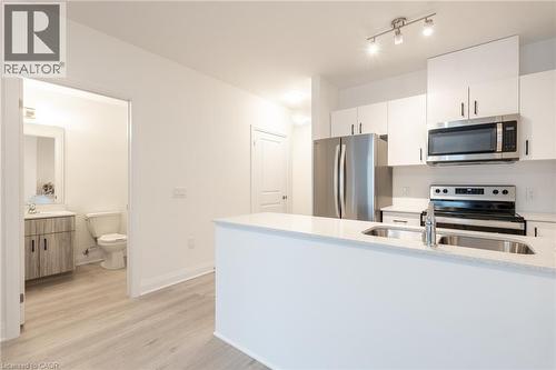 Modern kitchen featuring white cabinetry, stainless steel appliances, and a double basin sink set within a light-colored countertop - 1936 Rymal Road E Unit# 512, Hamilton, ON - Indoor Photo Showing Kitchen With Stainless Steel Kitchen