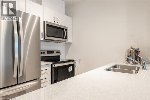 Kitchen featuring stainless steel appliances, white cabinetry, a dual basin sink, and a light-toned countertop - 1936 Rymal Road E Unit# 512, Hamilton, ON - Indoor Photo Showing Kitchen With Stainless Steel Kitchen With Double Sink