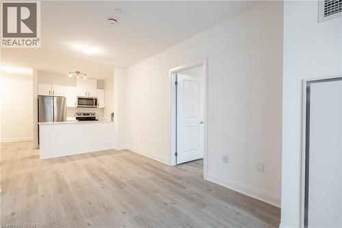 Open-concept living space featuring wood-finish flooring, white baseboards, and neutral wall paint - 1936 Rymal Road E Unit# 512, Hamilton, ON - Indoor Photo Showing Kitchen