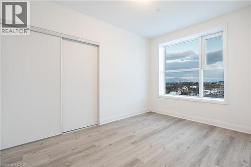 Light wood-finish flooring with white baseboards and neutral wall paint - 1936 Rymal Road E Unit# 512, Hamilton, ON - Indoor Photo Showing Other Room
