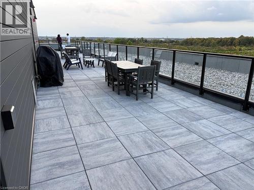 Spacious rooftop patio featuring large format pavers, modern glass railings, and expansive exterior siding - 1936 Rymal Road E Unit# 512, Hamilton, ON - Outdoor With Exterior