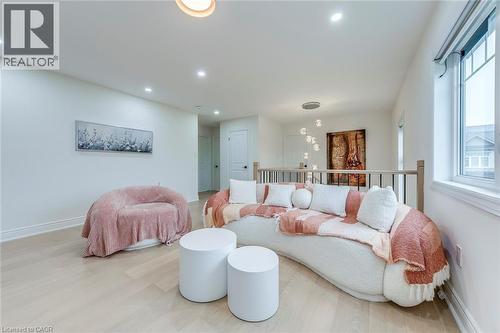 Bright open concept area featuring light wood-finish flooring, recessed lighting, a large window, and a wood and metal railing - 3937 Leonardo Street, Burlington, ON - Indoor Photo Showing Living Room