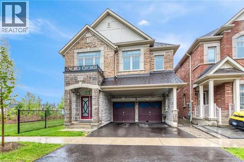 Two-story residence featuring a brick and stone facade, covered front entry, two-car garage with car port, and second-story balcony with iron railing - 3937 Leonardo Street, Burlington, ON - Outdoor With Facade