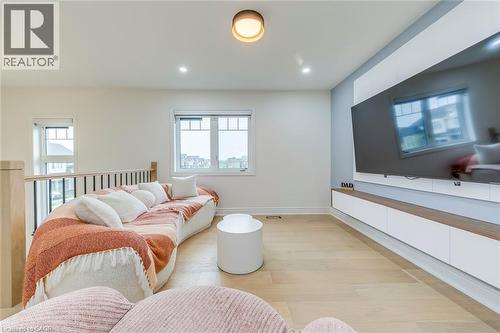 Open-concept space featuring light wood-finish flooring and a built-in entertainment unit with white cabinetry and a wood-tone accent shelf - 3937 Leonardo Street, Burlington, ON - Indoor Photo Showing Bedroom