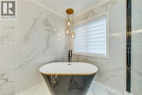 Freestanding soaking tub with a dark finish and gold accent rim - 3937 Leonardo Street, Burlington, ON - Indoor Photo Showing Bathroom