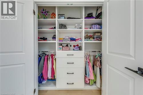 Custom closet system featuring multiple shelves, hanging rods, and four drawers with black hardware - 3937 Leonardo Street, Burlington, ON - Indoor With Storage