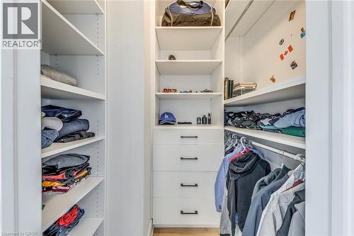 Custom-designed closet system featuring white shelving, multiple hanging rods, and integrated drawer storage with matte black hardware - 3937 Leonardo Street, Burlington, ON - Indoor With Storage